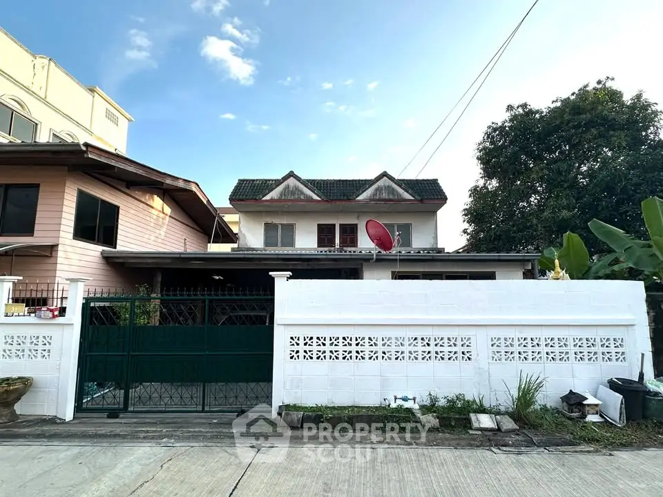 Charming two-story house with a gated entrance and lush greenery, perfect for family living.