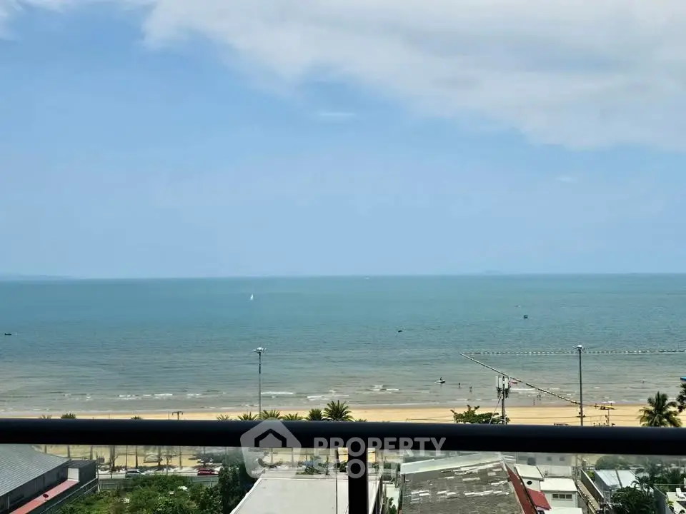 Stunning beachfront view from a high-rise balcony overlooking the ocean and sandy beach.