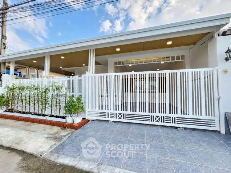 Modern single-story house with white fence and spacious driveway.