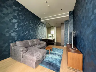Modern living room with stylish blue geometric wallpaper and cozy gray sofa
