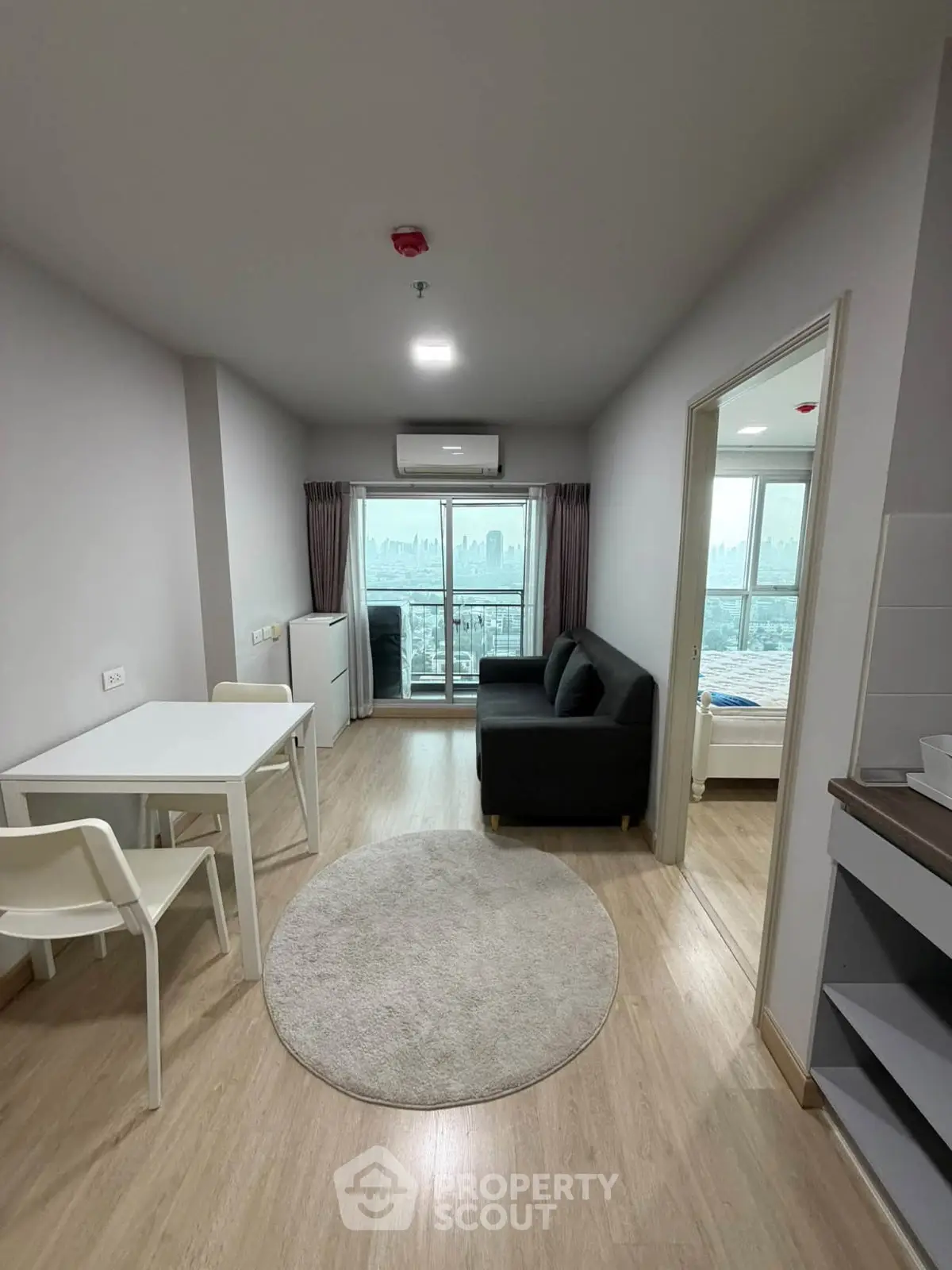 Modern apartment living room with city view, featuring sleek furniture and natural light.