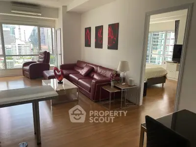 Spacious modern living room with red leather sofas and city view, adjacent to a cozy bedroom.