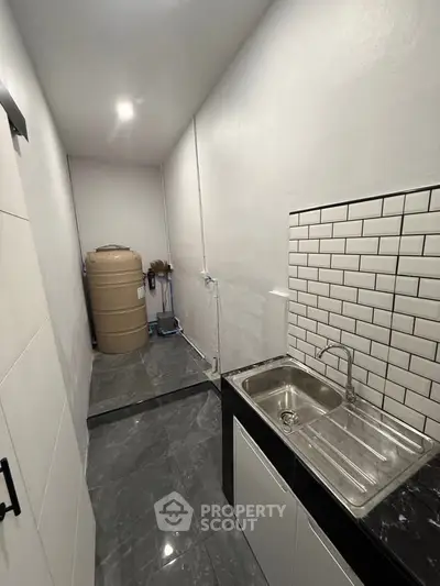 Compact kitchen area with sleek black countertops and white subway tiles.