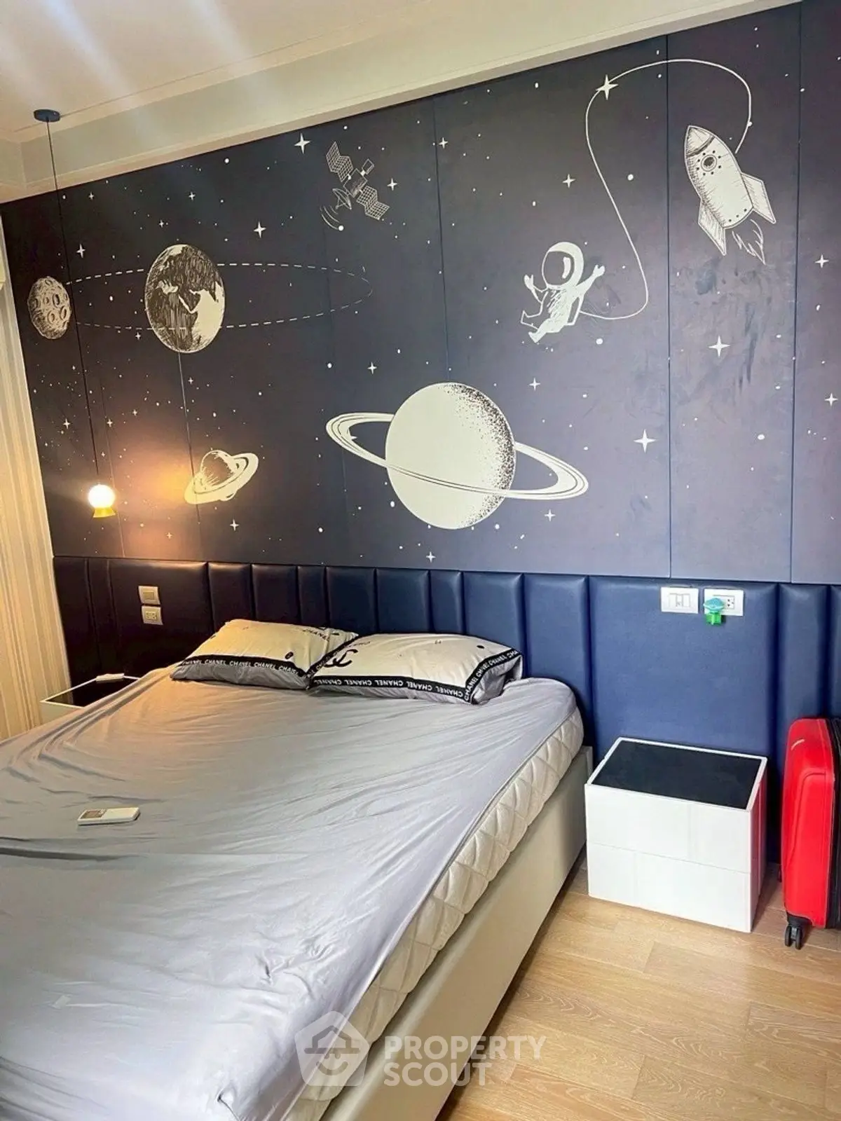 Stylish bedroom with space-themed wall art and modern furnishings.