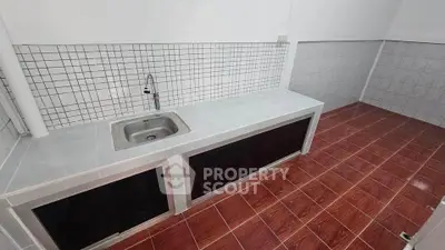 Spacious kitchen with tiled countertops and sink, ideal for culinary enthusiasts.