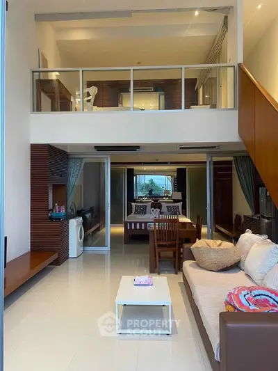 Spacious modern living room with mezzanine and open layout, featuring stylish furniture and natural light.