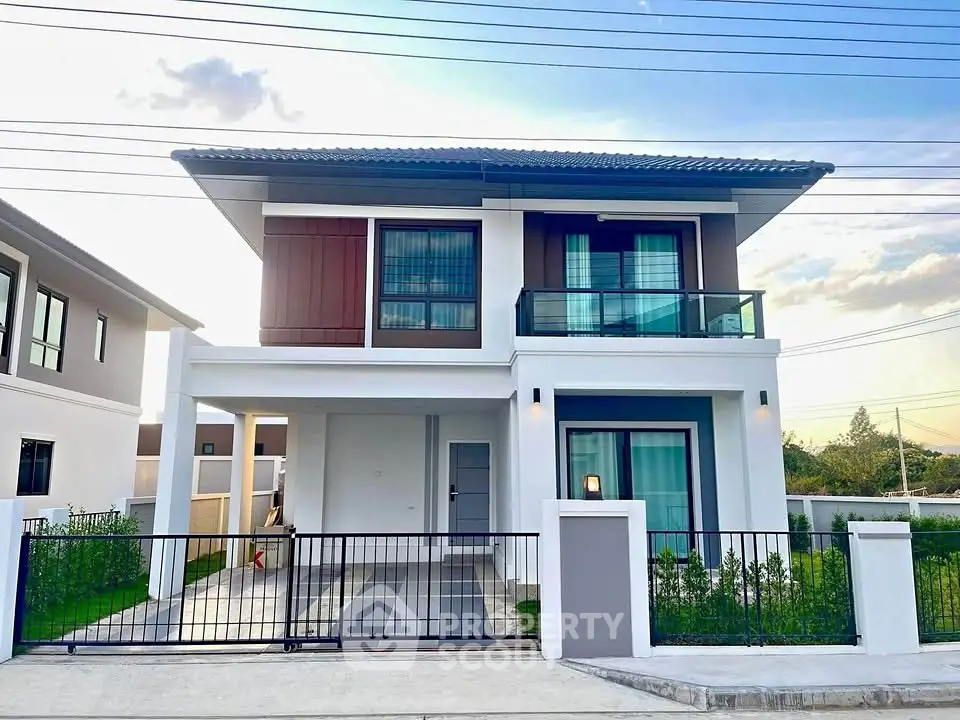 Modern two-story house with balcony and gated driveway in suburban neighborhood.