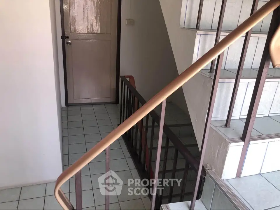 Staircase and hallway in a residential building with tiled flooring.