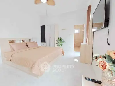Spacious modern bedroom with elegant decor and large TV, perfect for relaxation.