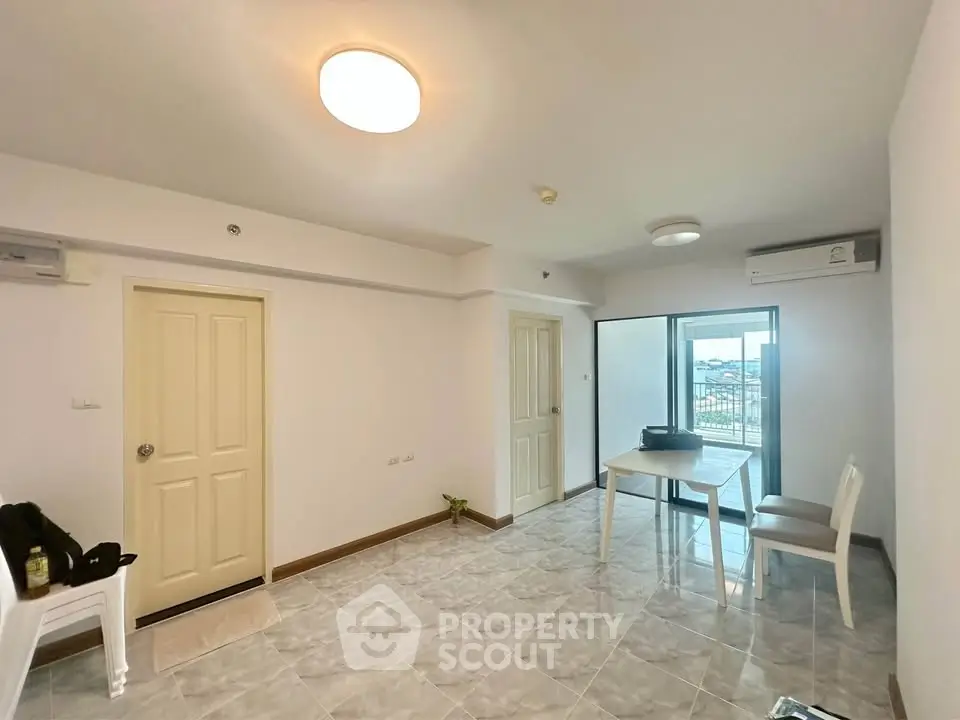 Spacious living room with modern tile flooring and balcony access