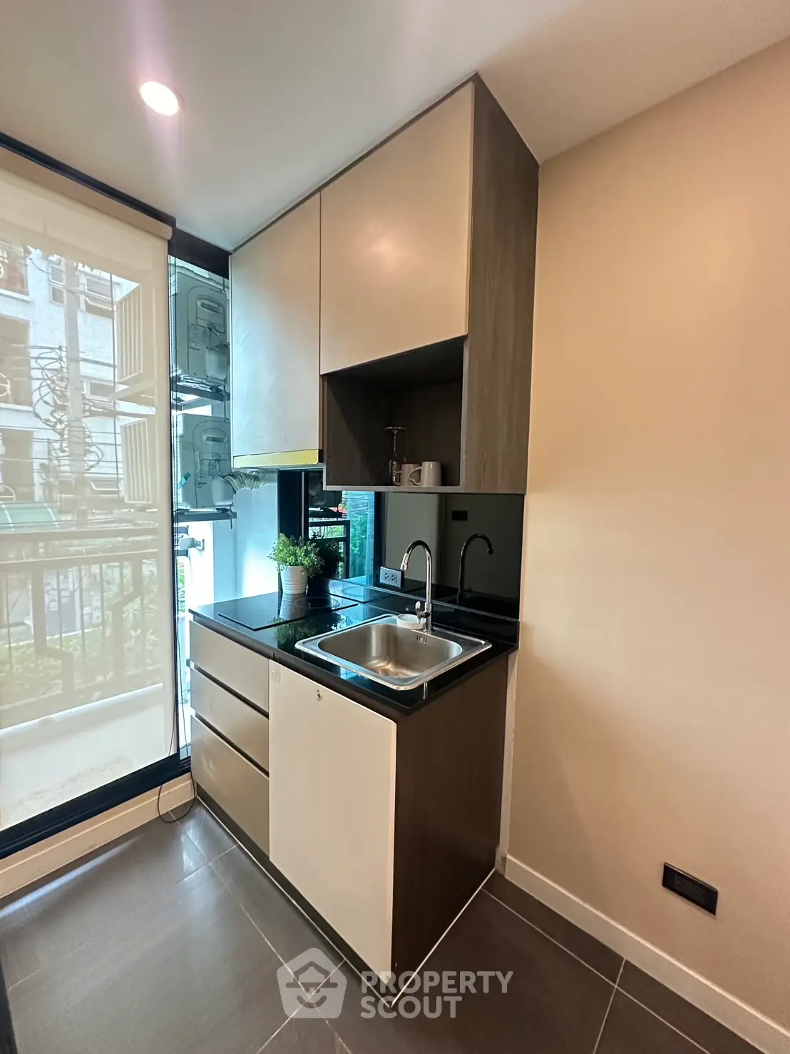 Modern compact kitchen with sleek cabinetry and large window view.