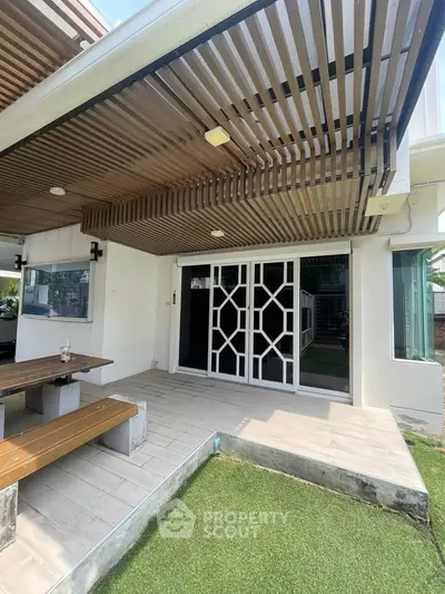 Modern patio with stylish wooden pergola and sliding glass doors leading to a spacious outdoor area.