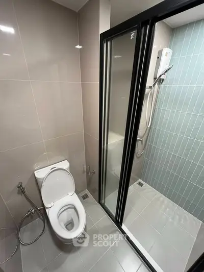 Modern bathroom with sleek shower and toilet in contemporary apartment.