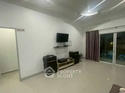 Spacious living room with modern TV setup and sliding glass doors.