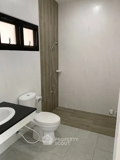 Modern bathroom with sleek design and neutral tones, featuring a shower and toilet.