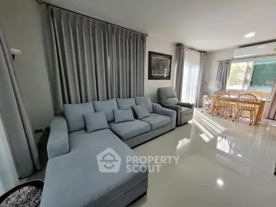 Spacious living room with modern gray sofa and dining area, perfect for family gatherings.