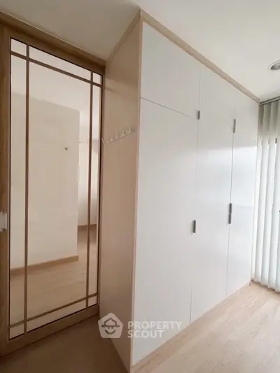 Modern white wardrobe with mirrored sliding door in a bright room