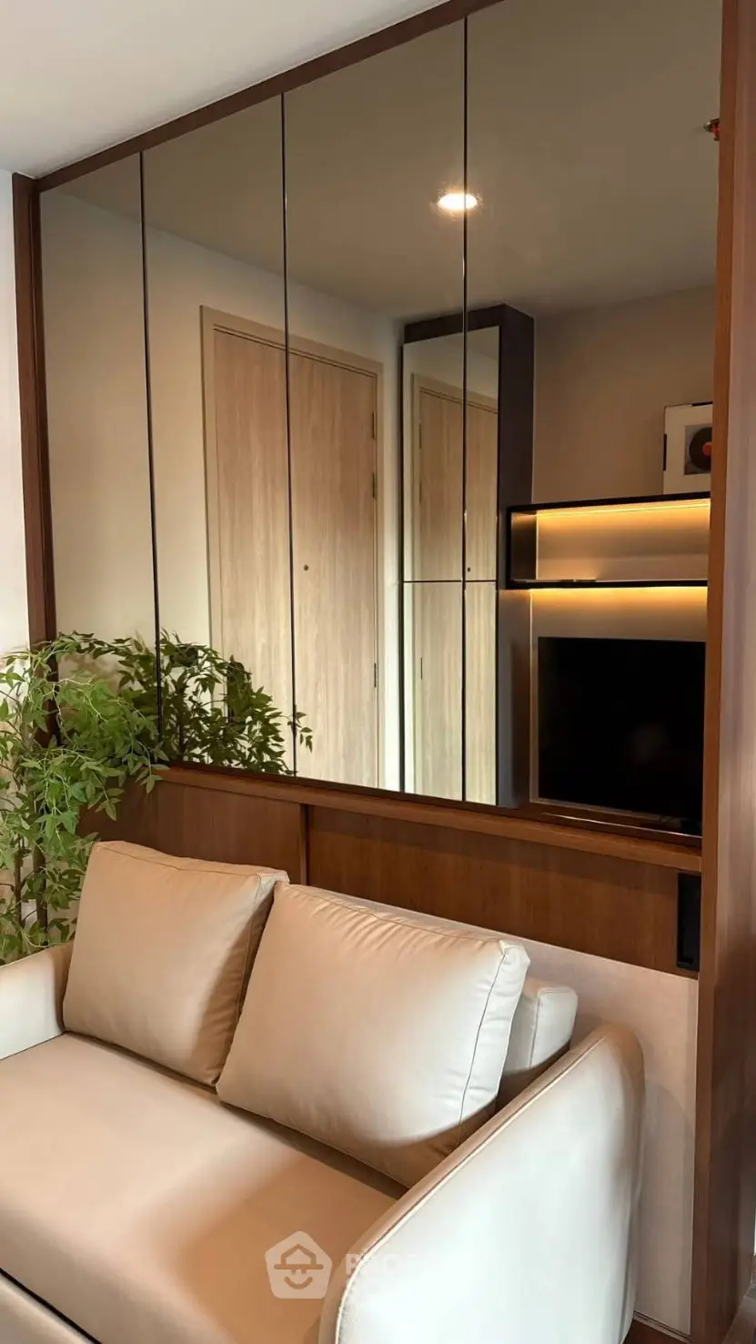 Modern living room with stylish sofa and mirrored wall, enhancing space and elegance.