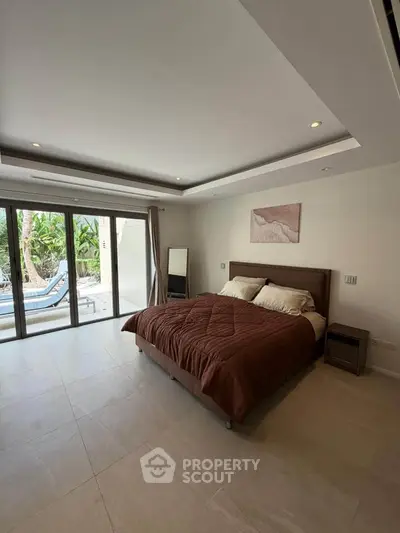 Spacious bedroom with modern decor and large windows opening to a garden view, perfect for relaxation.