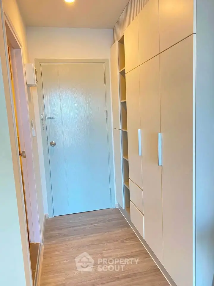 Modern hallway with built-in storage and wooden flooring in a contemporary apartment.