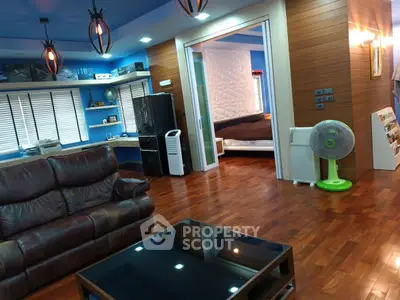 Spacious living room with modern decor and open view to bedroom, featuring hardwood floors and stylish lighting.