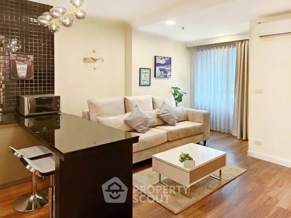 Modern living room with stylish decor and open kitchen layout, featuring cozy sofa and elegant lighting.