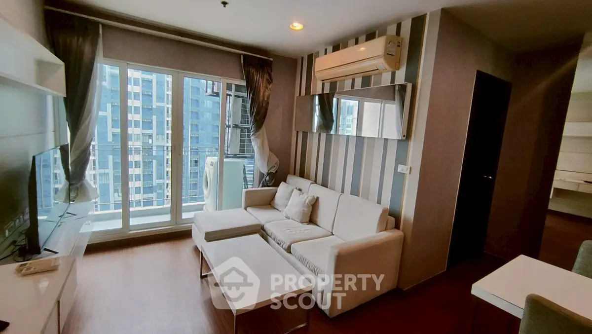 Modern living room with large windows and stylish decor in a high-rise apartment.