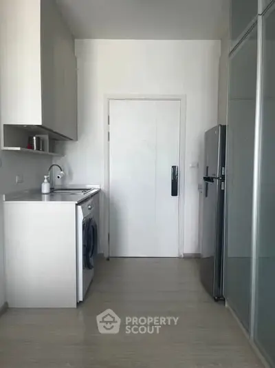 Modern kitchen with sleek appliances and minimalist design, featuring a washing machine and refrigerator.
