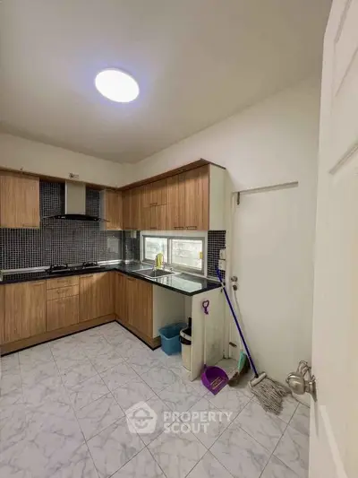 Spacious kitchen with modern wooden cabinets and tiled flooring