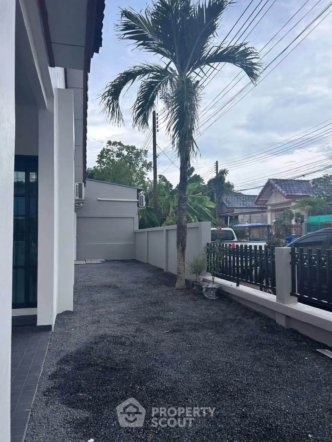 Charming residential exterior with palm tree and modern fence in a serene neighborhood setting.