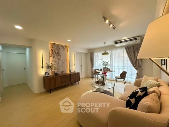 Spacious living room with elegant decor and natural light, featuring a cozy sofa and stylish lighting.