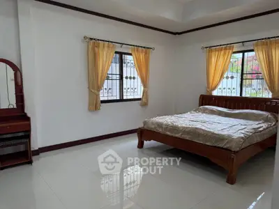Spacious bedroom with elegant wooden bed and natural light from large windows.