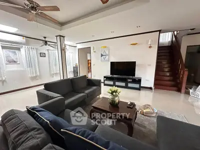 Spacious living room with modern furniture and staircase in a cozy home.