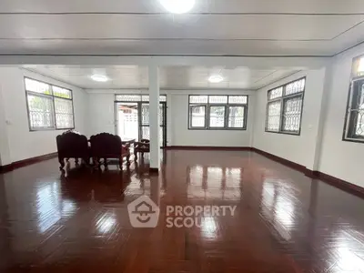 Spacious living room with polished wooden floors and elegant dining set