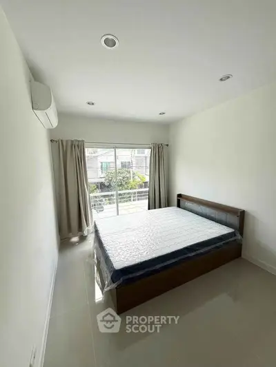 Bright bedroom with large window and modern bed in a minimalist style.