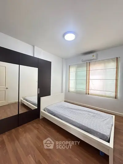 Spacious bedroom with wooden flooring and large wardrobe in modern apartment