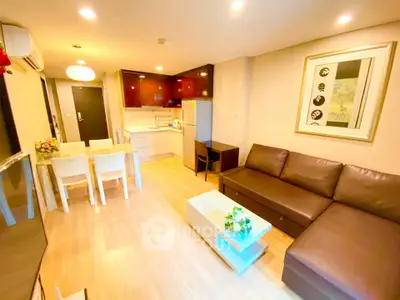 Modern living room with open kitchen, stylish decor, and cozy seating area in a well-lit apartment.