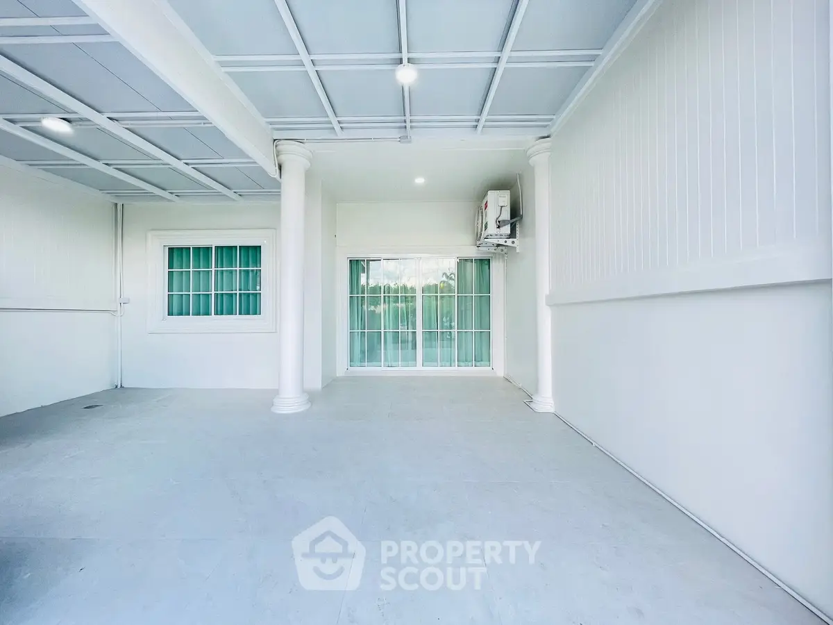 Spacious covered parking area with elegant columns and sliding glass doors.