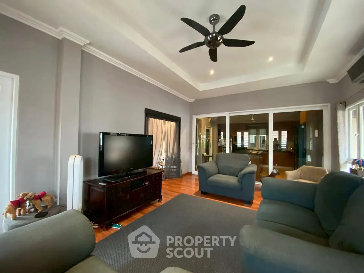 Spacious living room with modern decor and ceiling fan, perfect for relaxation.