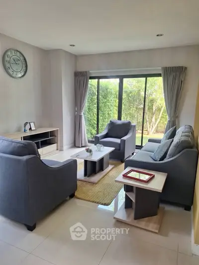 Charming living room with modern furniture and large window overlooking lush greenery.