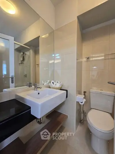 Modern bathroom with sleek fixtures and elegant tile design, featuring a spacious sink and contemporary toilet.