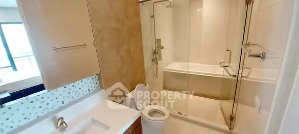 Modern bathroom with glass-enclosed shower and sleek fixtures.