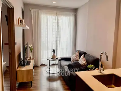 Cozy modern living room with sleek furniture and natural light from large window.