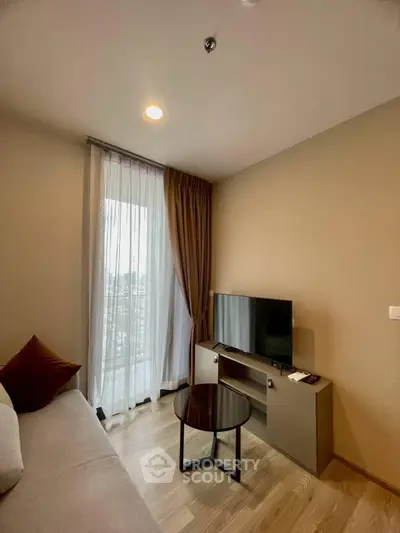 Modern living room with cozy sofa, flat-screen TV, and city view through large window.