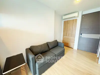 Modern living room with sleek black sofa and wooden flooring, featuring a minimalist design.
