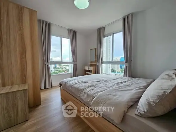 Modern bedroom with city view, featuring wooden furniture and large windows.