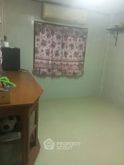 Cozy room with air conditioning and floral curtains, ideal for a small study or storage space.