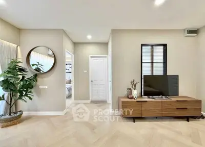 Modern living room with stylish decor and natural light, featuring a TV stand and elegant flooring.
