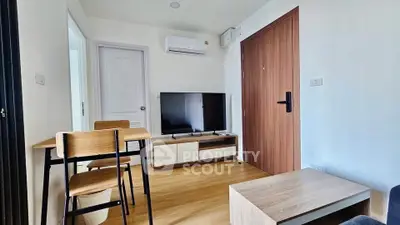 Modern living room with wooden flooring, TV, and dining area in a cozy apartment.