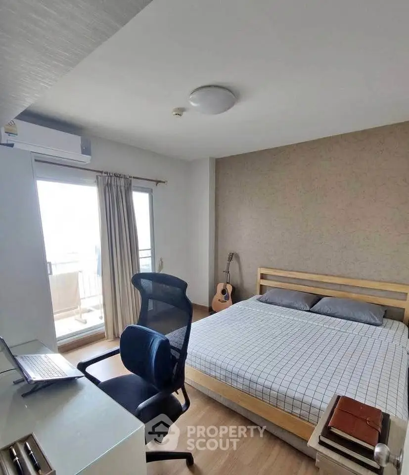 Modern bedroom with balcony access, featuring a cozy bed, work desk, and natural light.